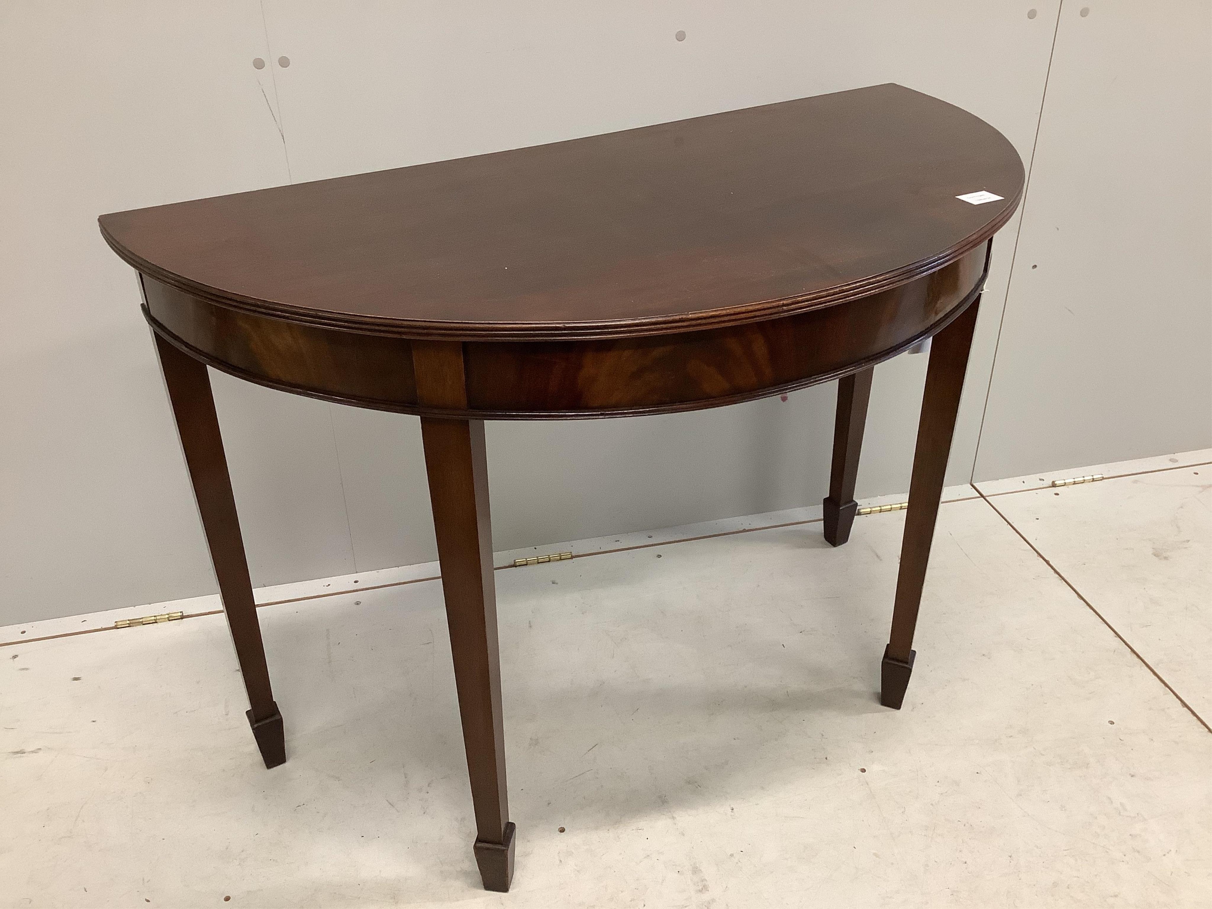 A George III style mahogany demi-lune console table on tapered legs and spade feet, width 114cm, depth 58cm, height 81cm. Condition - fair